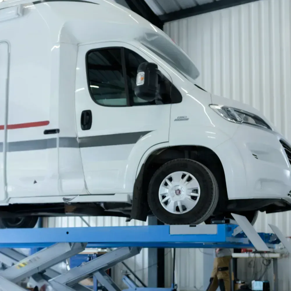 Matkailuauto nosturilla korjaamolla